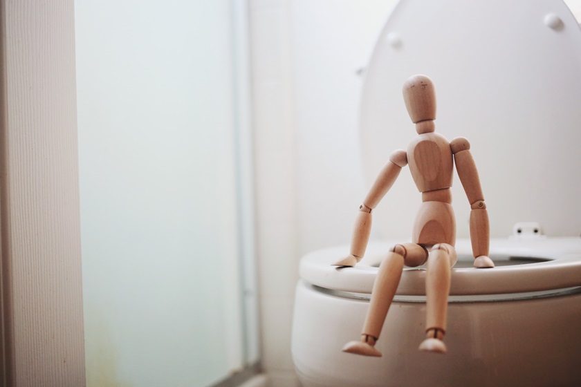Croquis-dukke i træ sidder på et toilet