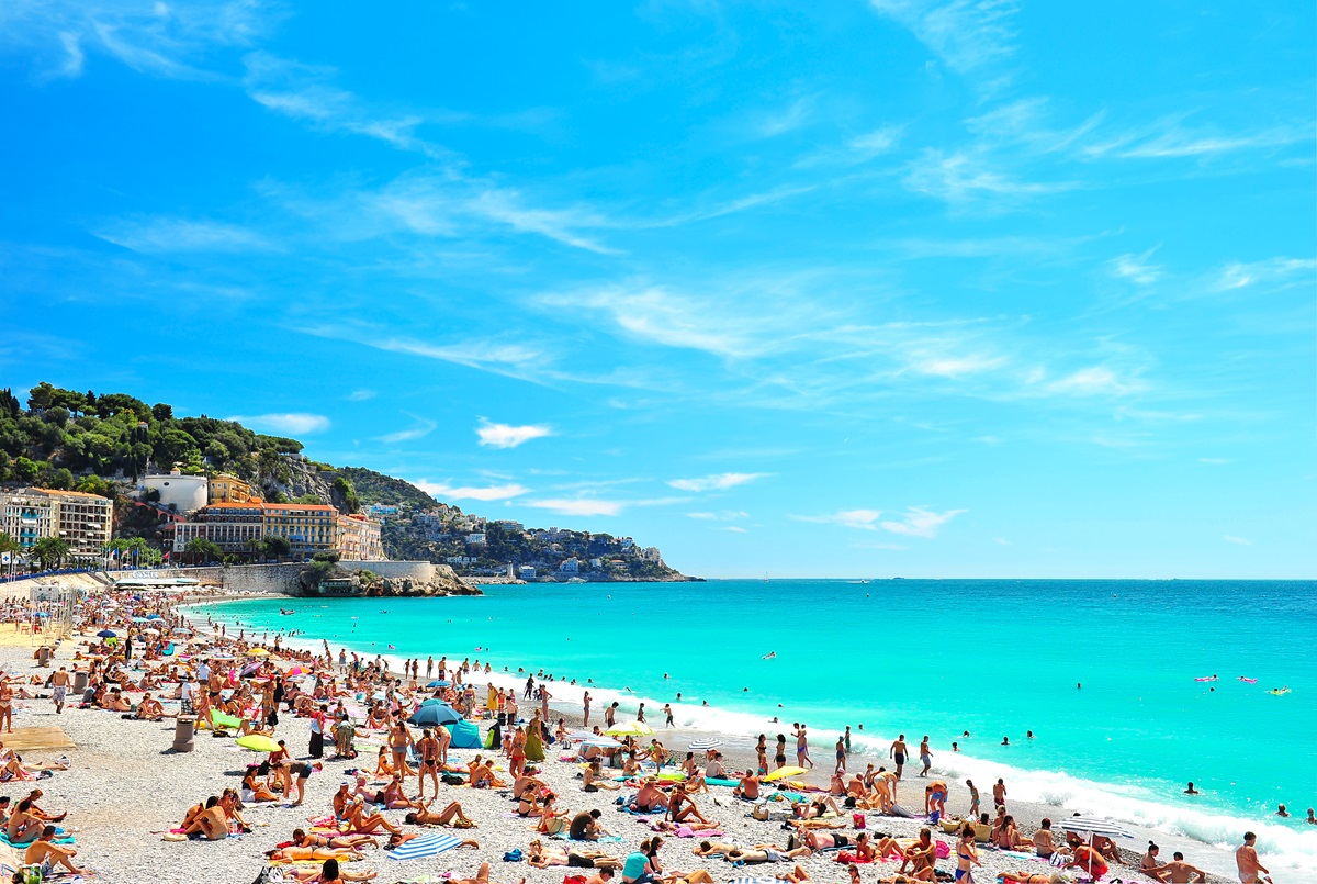 Sandstrand fyldt med mennesker ved turkisblåt hav  