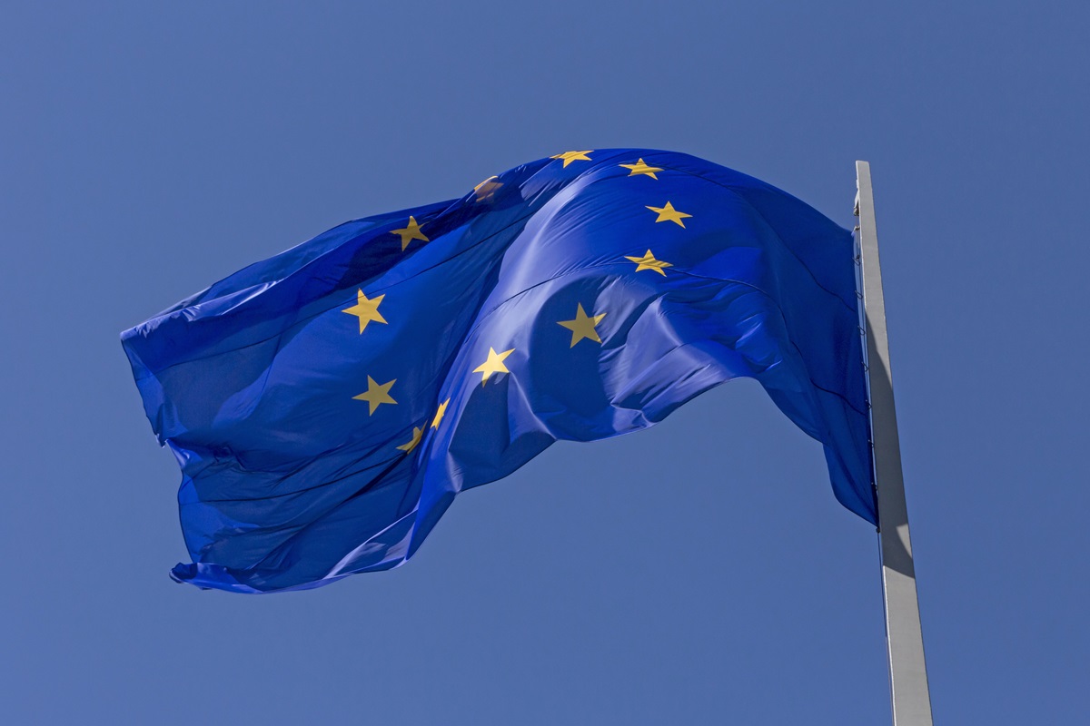 Blåt EU-flag med gule stjerne blafrer i vinden