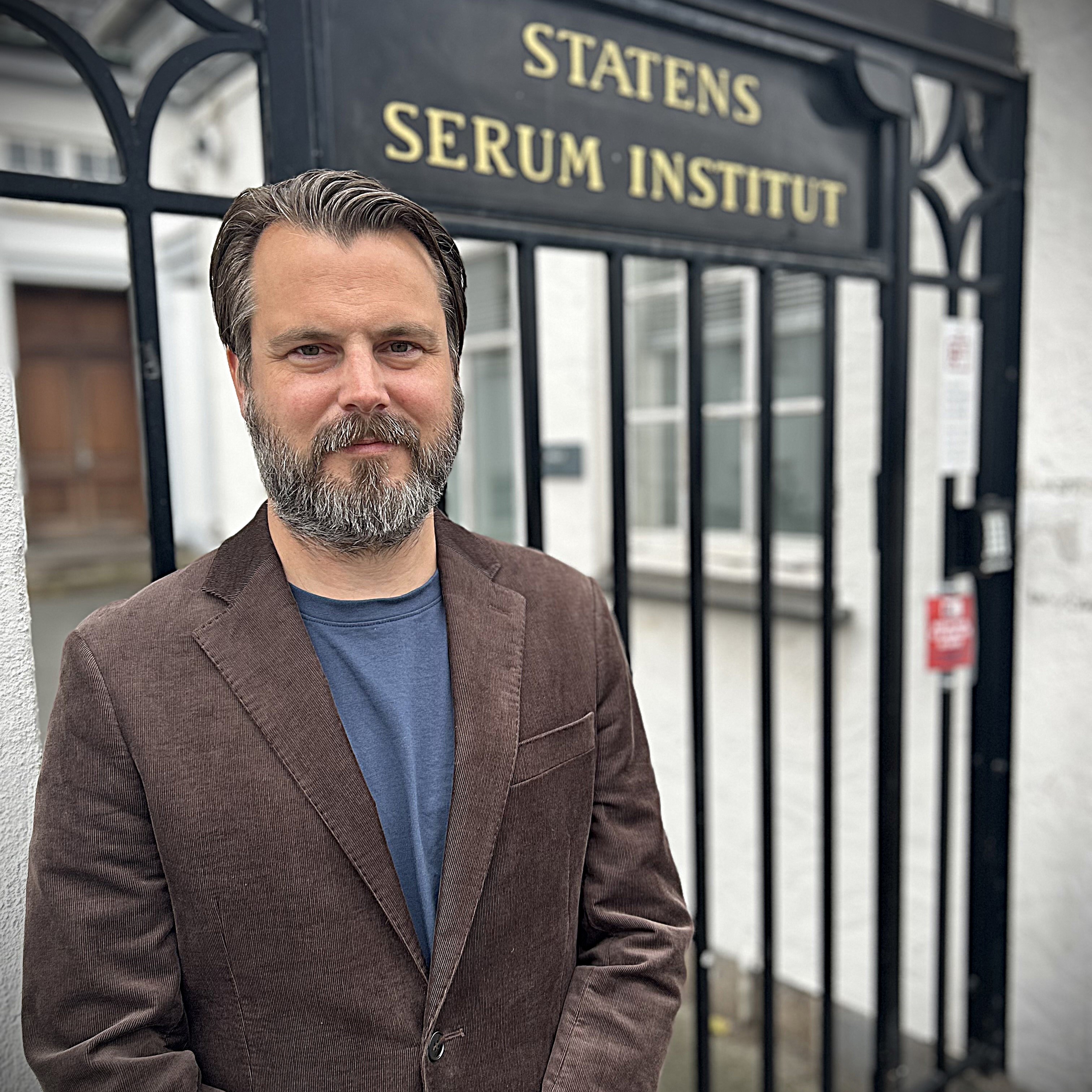 Mand står foran port, hvor der står Statens Serum Institut