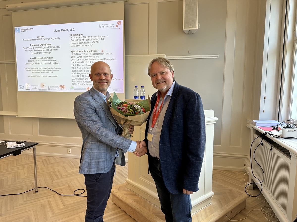 To mænd giver hinanden hånd, og den ene overrækker en buket blomster til den anden