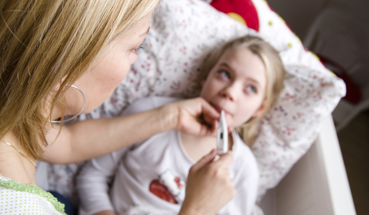 Kvinder der tager temperaturen på en pige. 