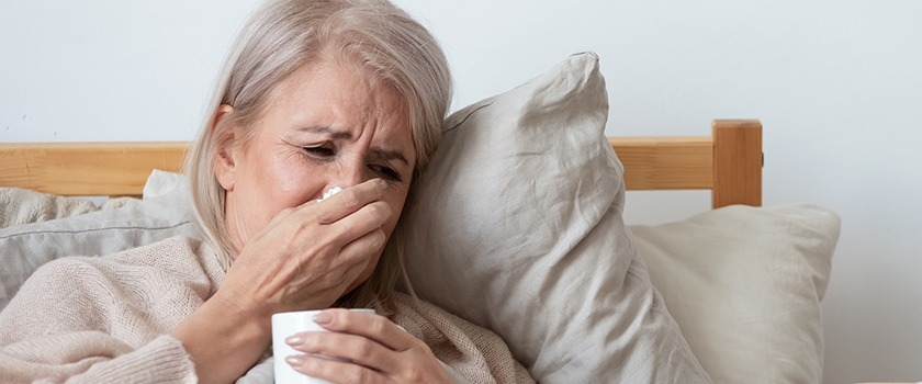 Kvinde ligger i sengen med influenza
